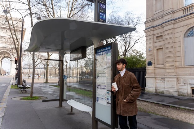 Jeune français attendant à la gare le bus et buvant du café