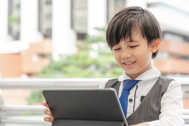 Jeune garçon à l'aide d'une tablette de téléphone intelligent sur le quartier des affaires urbain, concept de l'éducation