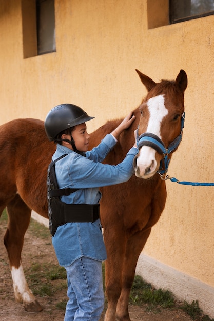 Photo gratuite jeune garçon apprenant à monter à cheval