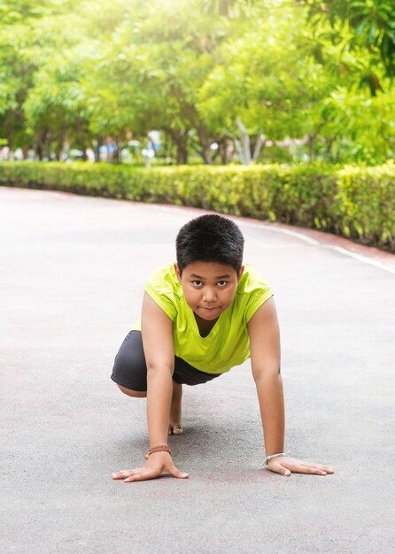 Photo gratuite un jeune garçon asiatique se prépare à courir sur la piste dans le jardin pendant la journée pour s'entraîner