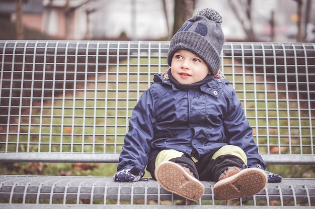 Photo gratuite jeune garçon assis sur un banc