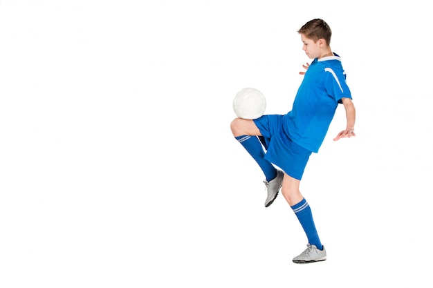 Jeune garçon avec un ballon de soccer faisant voler coup de pied