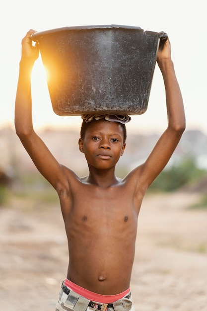 Photo gratuite jeune garçon avec bassin sur la tête