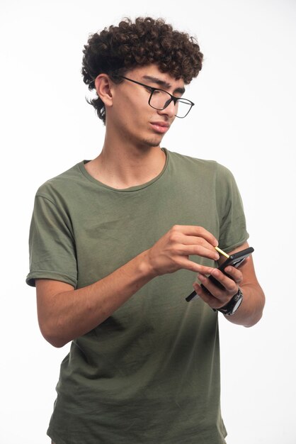 Jeune garçon avec une coiffure frisée écrivant un message avec surprise.