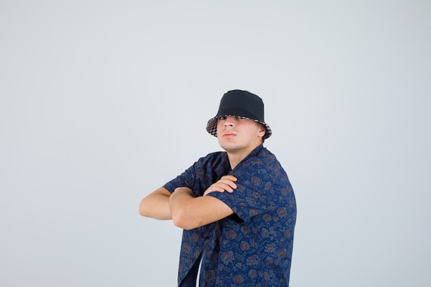 Jeune Garçon Debout Les Bras Croisés En Chemise à Fleurs, Casquette Et à L'air Confiant.