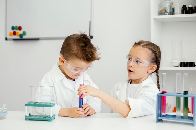 Jeune garçon et fille scientifiques avec des tubes à essai faisant des expériences en laboratoire