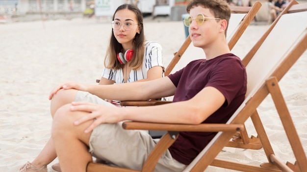 Jeune garçon et fille se détendre ensemble à la plage