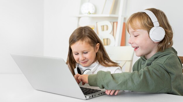 Jeune garçon et fille utilisant un ordinateur portable avec un casque