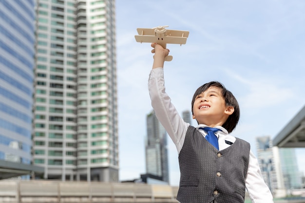 Jeune garçon jouant aviateur jouet avion avion imagination rêvant d'être un futur pilote sur le quartier des affaires urbain