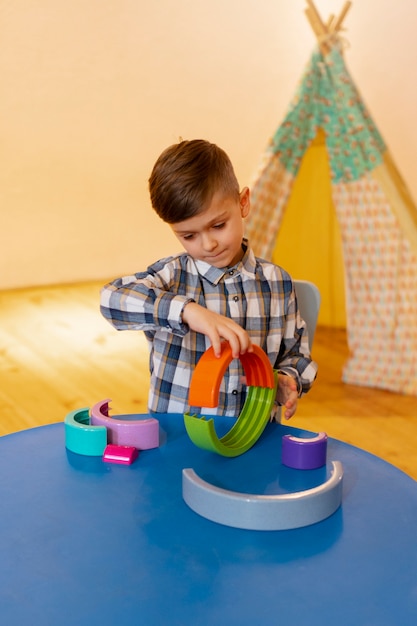 Photo gratuite jeune garçon jouant à l'intérieur avec des jouets écologiques