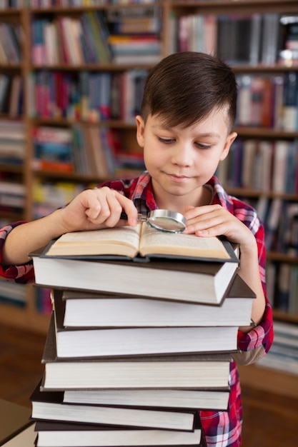 Jeune garçon, à, pile livres, lecture