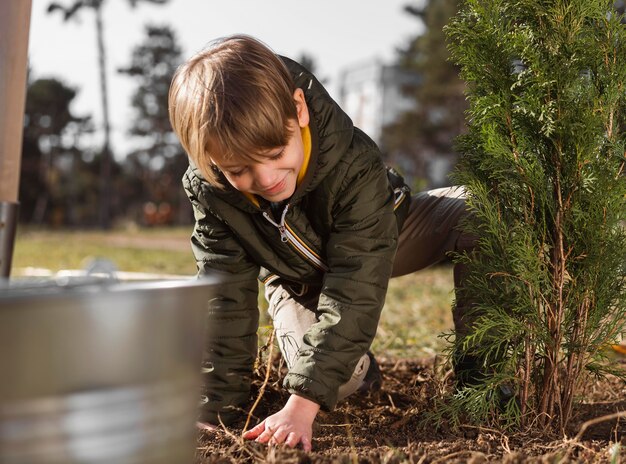 Jeune garçon plantant un arbre à l'extérieur