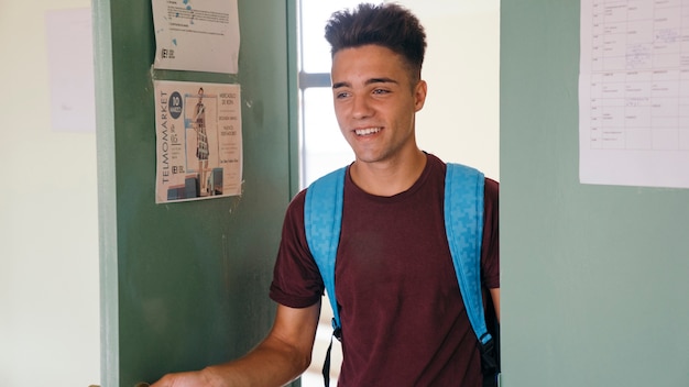 Photo gratuite jeune garçon avec un sac à dos entrant dans la salle de classe