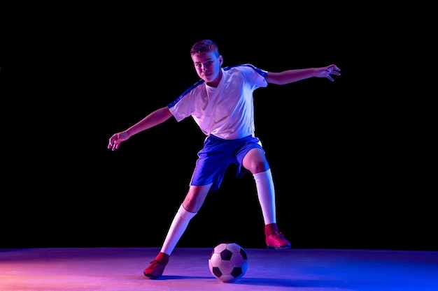 Jeune garçon en tant que joueur de football ou de football sur un mur sombre