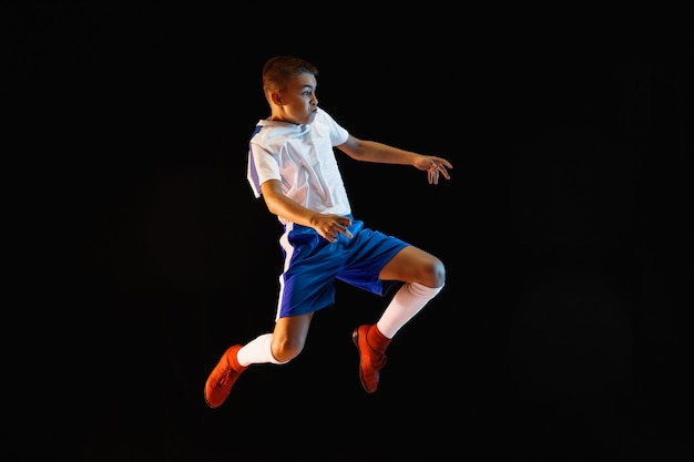 Jeune garçon en tant que joueur de football ou de football sur un mur sombre