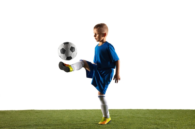 Photo gratuite jeune garçon en tant que joueur de football ou de football en tenue de sport faisant une feinte ou un coup de pied avec le ballon pour un but sur blanc.