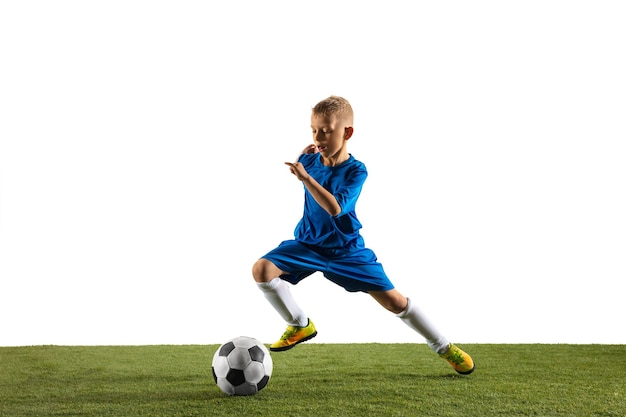 Photo gratuite jeune garçon en tant que joueur de football ou de football en tenue de sport faisant une feinte ou un coup de pied avec le ballon pour un but sur blanc.