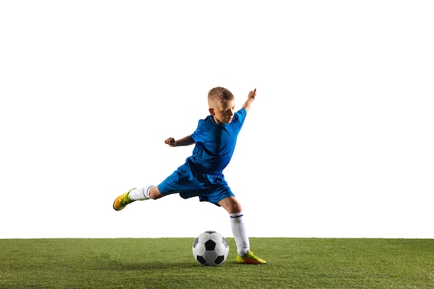 Jeune garçon en tant que joueur de football ou de football en vêtements de sport faisant une feinte ou un coup de pied avec le ballon pour un but sur fond de studio blanc. Fit jouer au garçon en action, mouvement, mouvement au jeu.