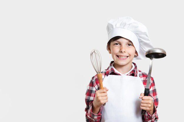 Jeune garçon tenant des ustensiles de cuisine