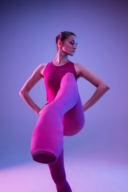 Jeune et gracieux danseur de ballet isolé sur fond violet studio en néon