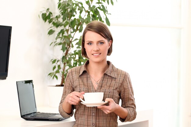 Jeune et heureuse femme avec une tasse de café