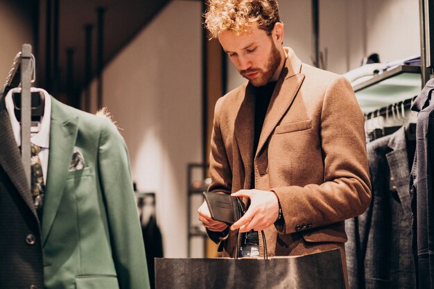 Jeune homme, acheter des chiffons et payer en espèces dans un magasin