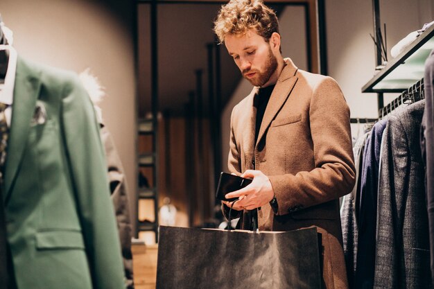 Jeune homme, acheter des chiffons et payer en espèces dans un magasin