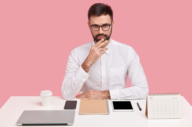 Jeune homme d'affaires assis au bureau avec des gadgets