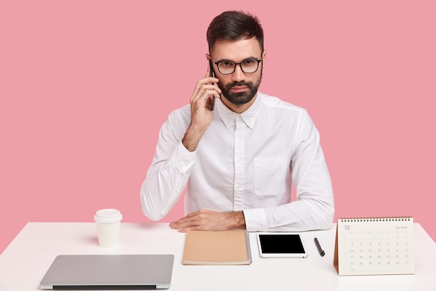 Jeune homme d'affaires assis au bureau avec des gadgets