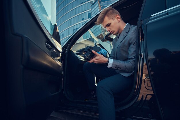 Un jeune homme d'affaires attrayant regarde son téléphone portable alors qu'il est assis dans la voiture.