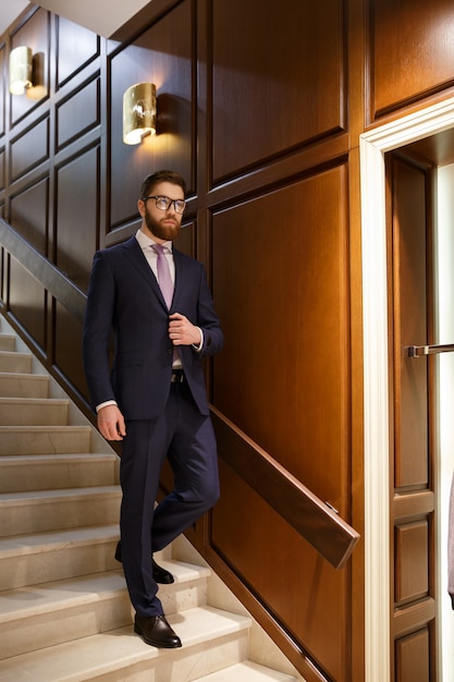 Jeune homme d'affaires barbu concentré sérieux sur une échelle