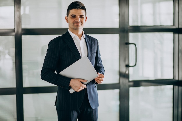 Jeune homme d'affaires beau avec ordinateur portable au bureau