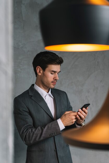 Jeune homme d&#39;affaires en costume à l&#39;aide de téléphone portable