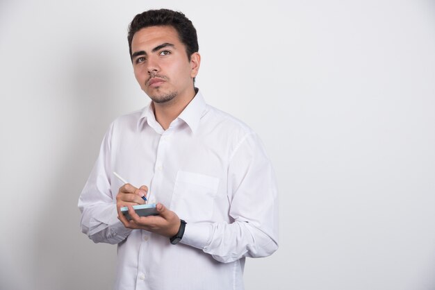 Jeune homme d'affaires écrit sur fond blanc.