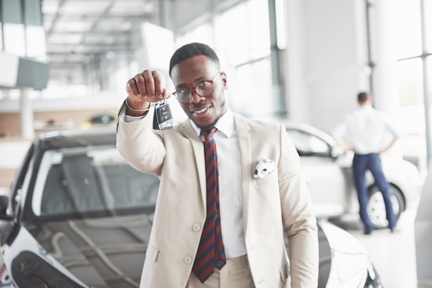 Le jeune homme d'affaires noir attrayant achète une nouvelle voiture, les rêves deviennent réalité.