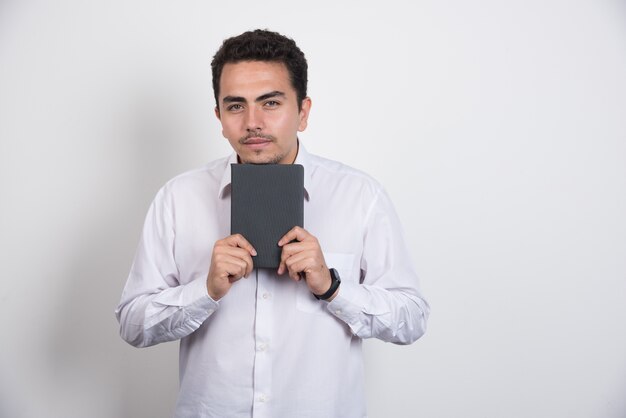 Jeune homme d'affaires posant avec ordinateur portable sur fond blanc.