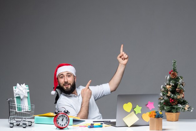 Jeune homme d'affaires positif avec le chapeau de père noël travaillant