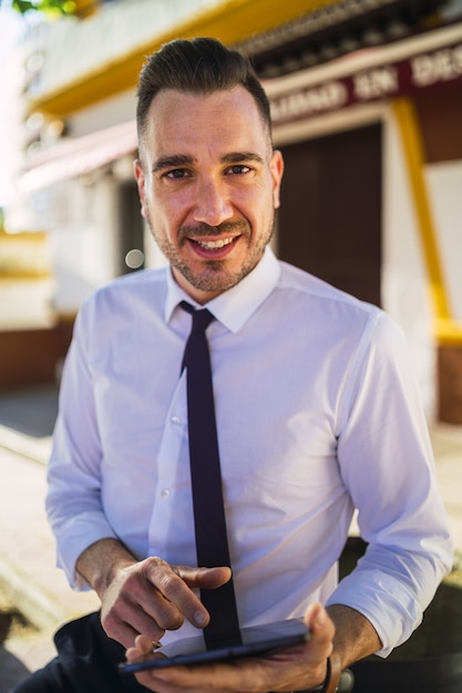 Photo gratuite jeune homme d'affaires prospère dans une tenue formelle à l'aide d'une tablette