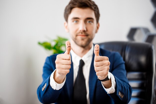 Jeune homme d'affaires prospère montrant bien sur le lieu de travail.