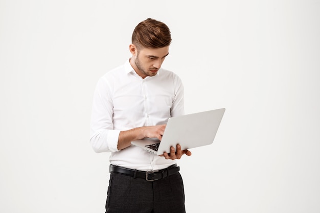 Jeune homme d'affaires prospère, tapant sur un ordinateur portable.