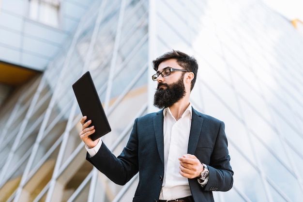 Jeune, homme affaires, regarder, tablette numérique, debout, devant, bâtiment