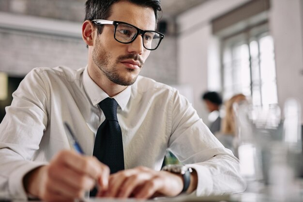 Jeune homme d'affaires sérieux travaillant à son bureau au bureau