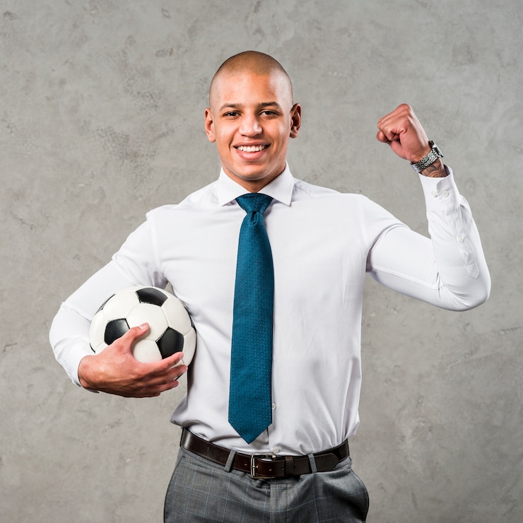 Photo gratuit jeune, homme affaires, tenant balle football, dans main, serrer, elle, poing, debout, contre, mur gris