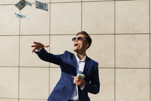 Jeune homme d&#39;affaires tourne autour des dollars et des danses dans la rue