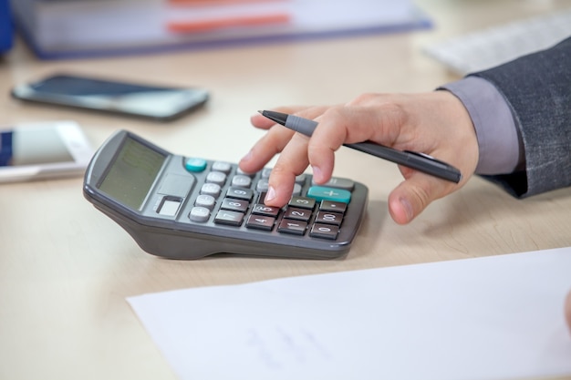 Jeune homme d'affaires travaillant depuis son bureau et calculant des nombres