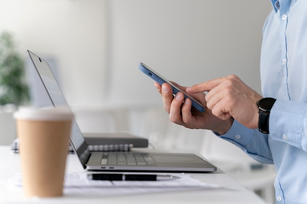 Jeune homme d'affaires travaillant à son bureau avec ordinateur portable et smartphone