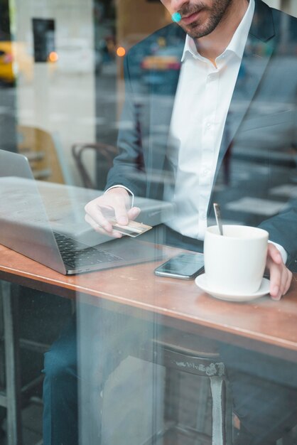 Jeune homme d&#39;affaires utilisant une carte de crédit pour payer sa facture au café