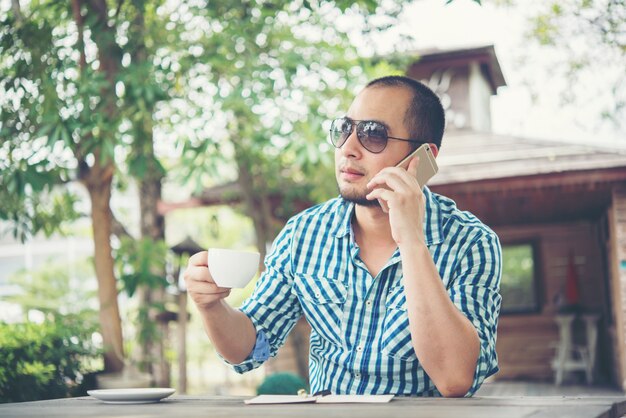 Jeune homme d&#39;affaires utilisant un smartphone tout en travaillant dans le jardin de la maison.