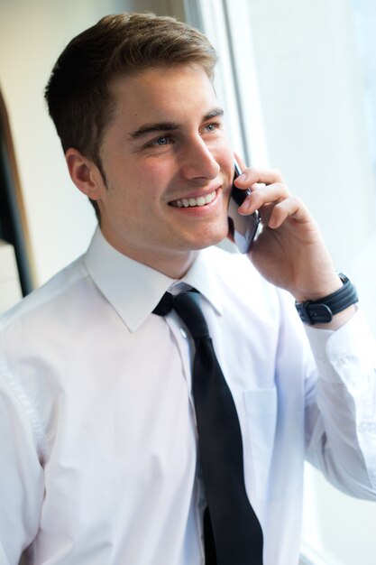 Jeune homme d&#39;affaires utilisant son téléphone portable en bureau.