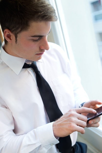 Jeune homme d&#39;affaires utilisant son téléphone portable en bureau.